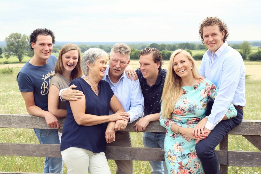Familie leunt op een houten hek in de natuur, familiefotografie