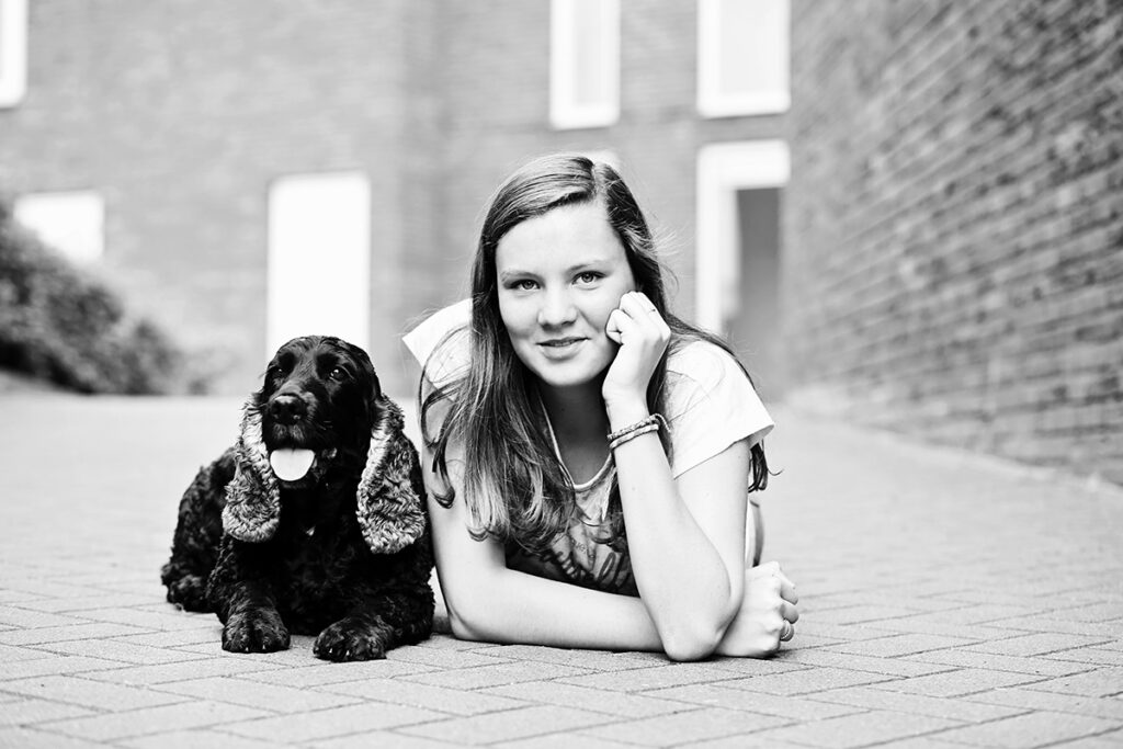 Zwart-witfoto van een meisje met twee spaniëls op straat