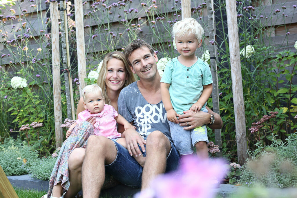 Gezin met twee kinderen op een bankje in de tuin, familieshoot buiten