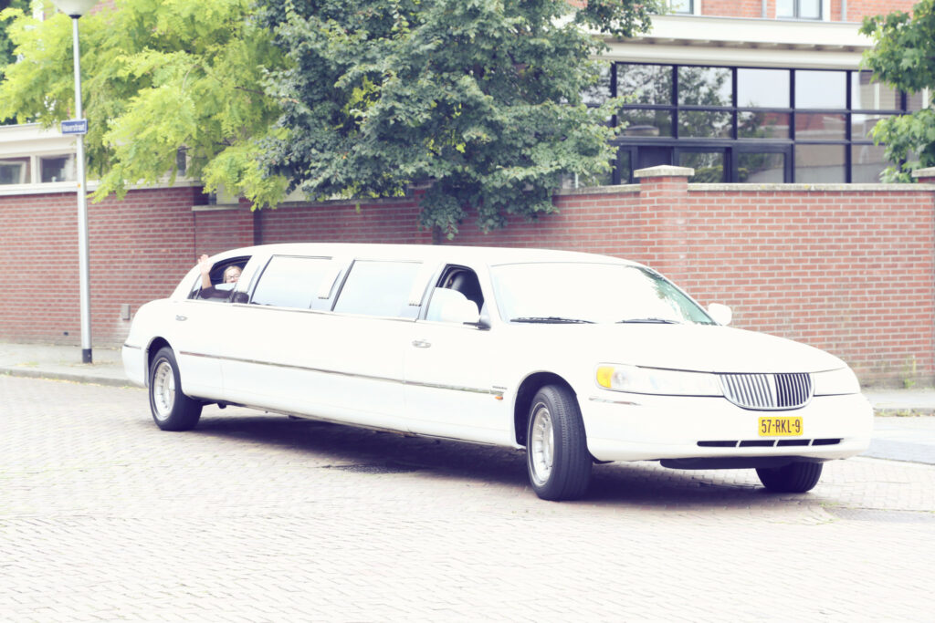 Witte stretchlimousine geparkeerd bij een bakstenen gebouw