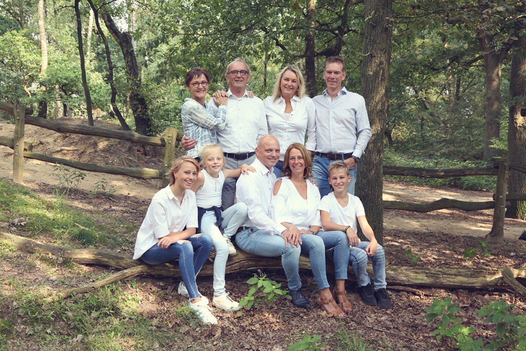 Grote familie samen in het bos op boomstammen