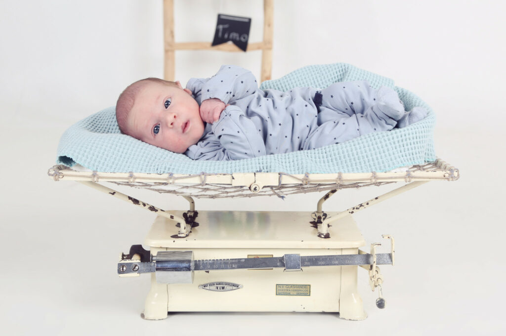 Newborn op een vintage babyweegschaal in de studio