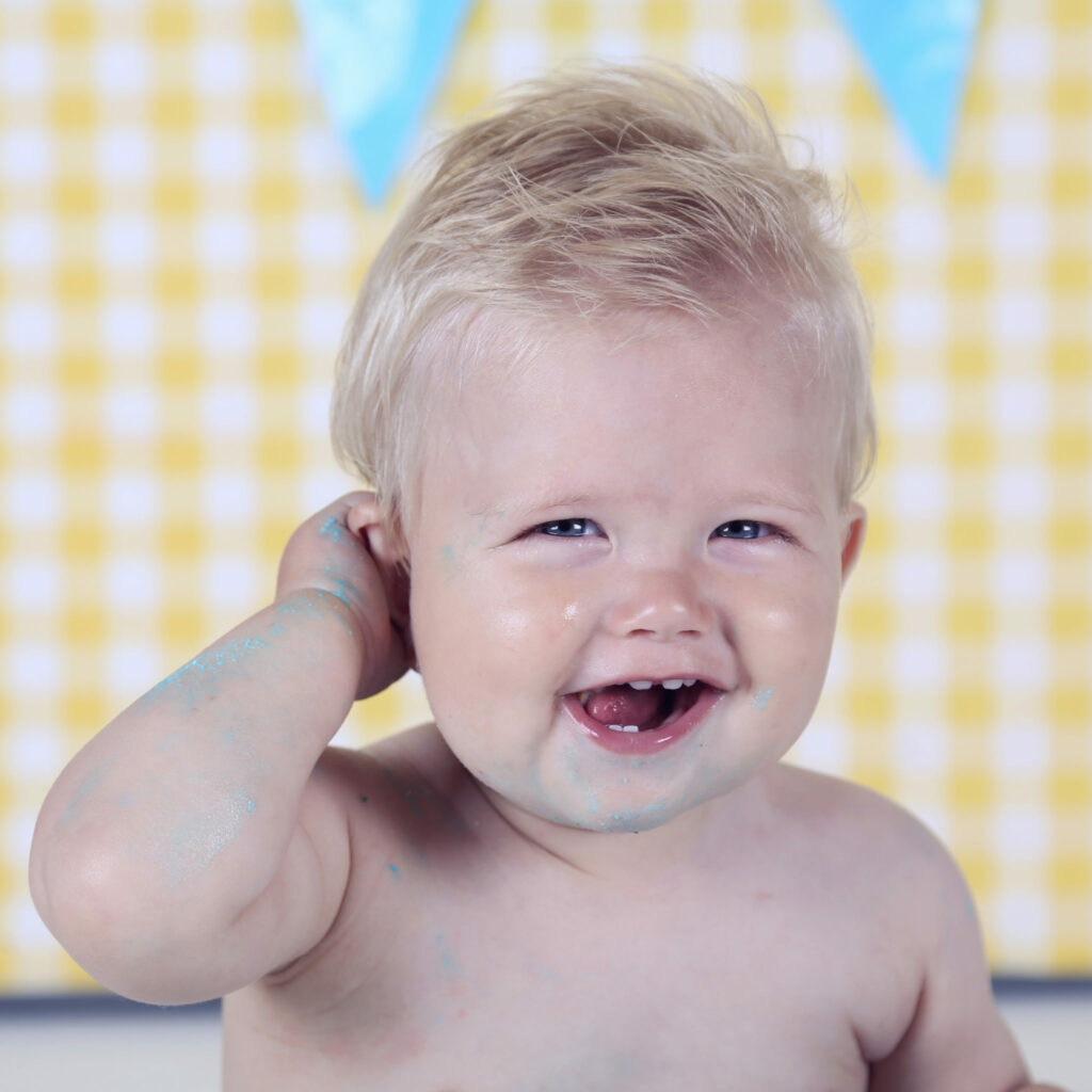 Lachende baby met de hand in het haar tegen een gele ruitachtergrond