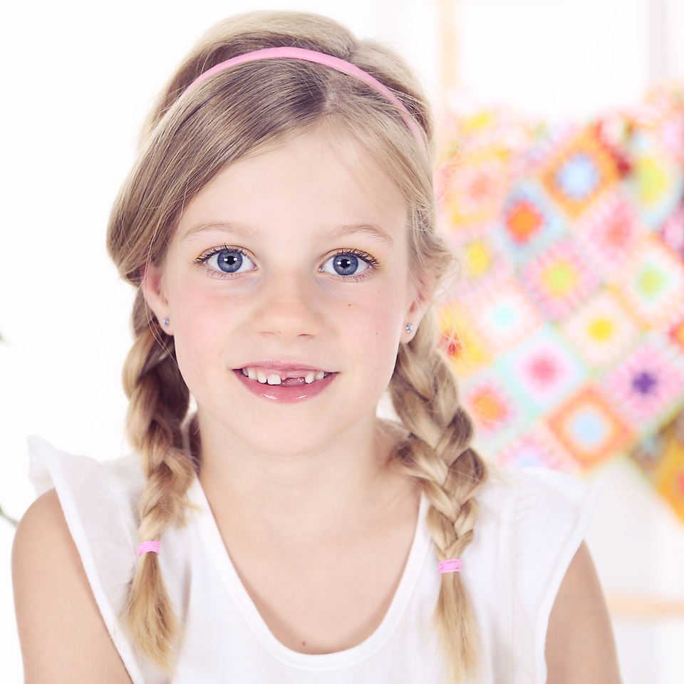 Portret van een lachend meisje met vlechten, kinderfotografie