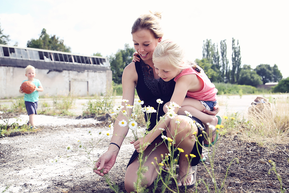 Moeder met dochter op schoot op een zonnig veld, familieshoot buiten