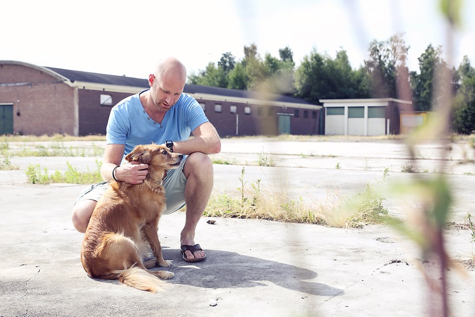 Man knuffelt zijn hond buiten op een zandvlakte