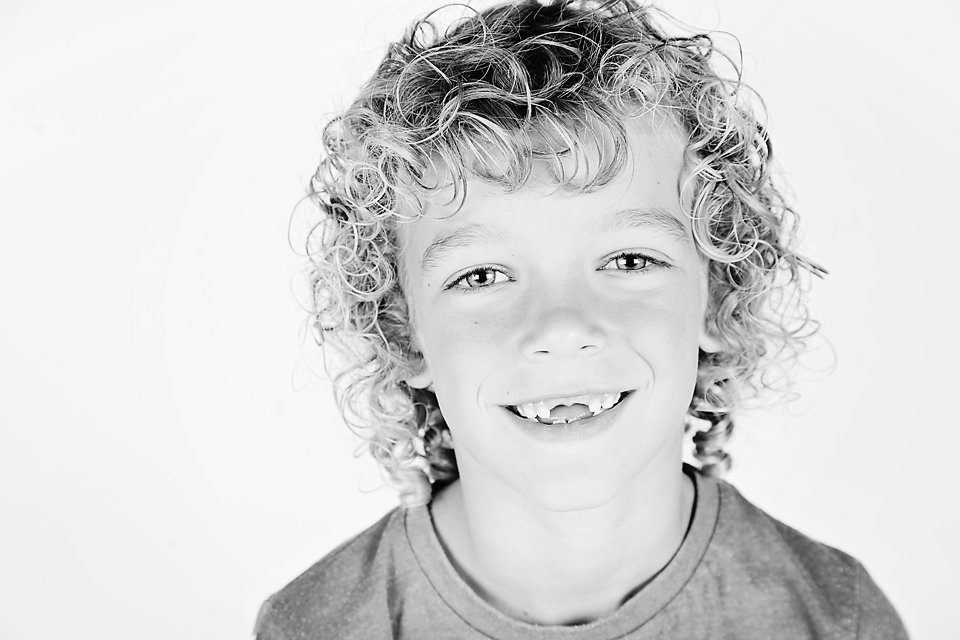 Zwart-witportret van een lachende jongen met krullen