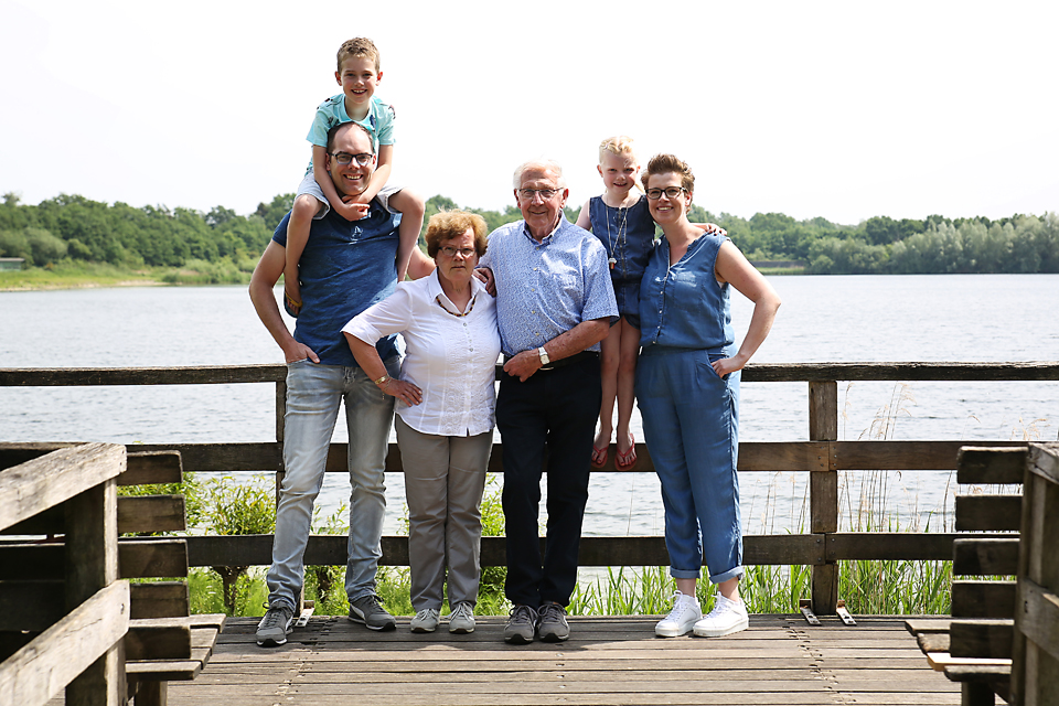 Familie met kinderen op schouders op een steiger bij het water