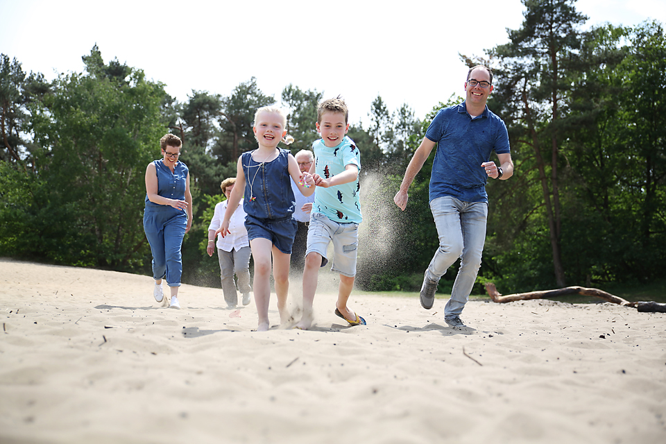 Gezin rent samen over het zand in het bos