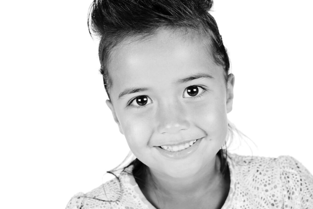 Zwart-witportret van een lachend meisje, kinderfotografie in de studio