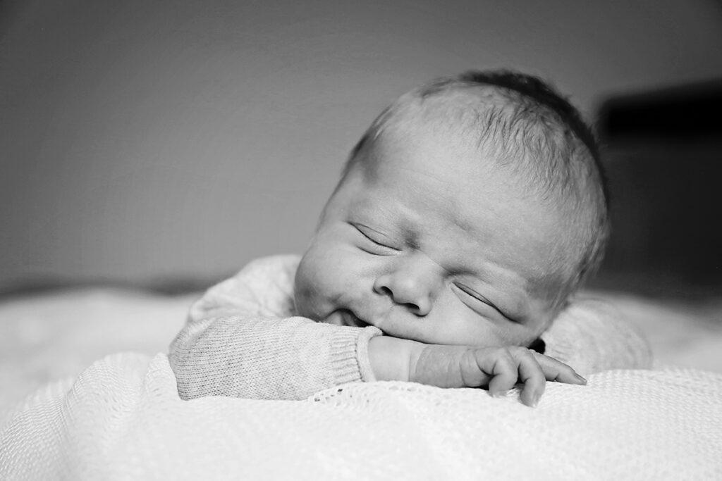 Zwart-witfoto van een glimlachende slapende newborn