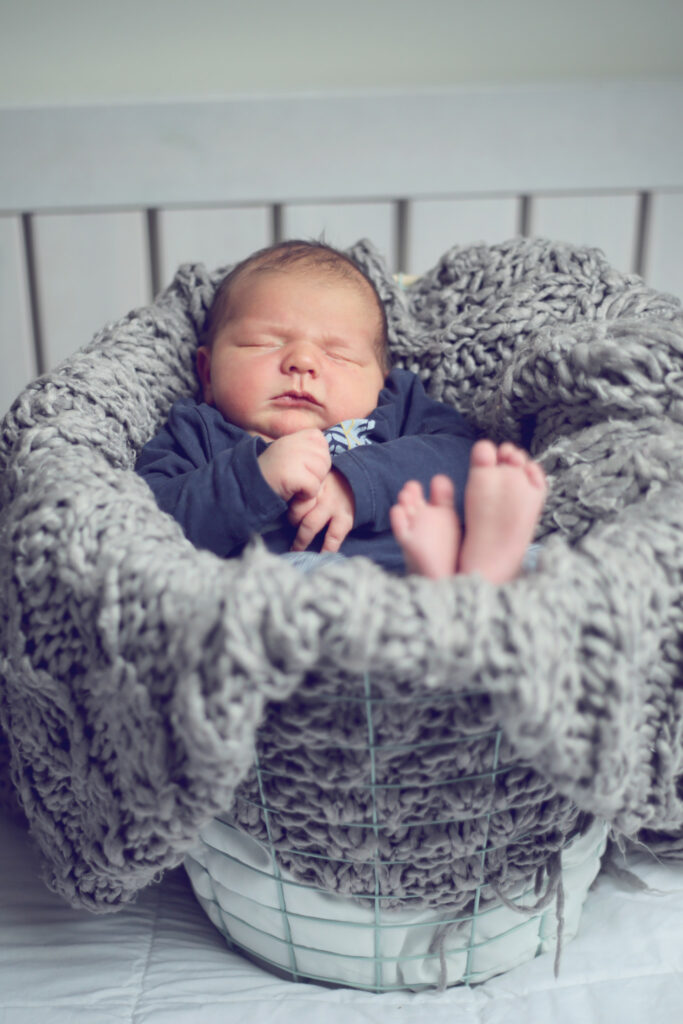 Slapende newborn in een mandje met grijze vacht