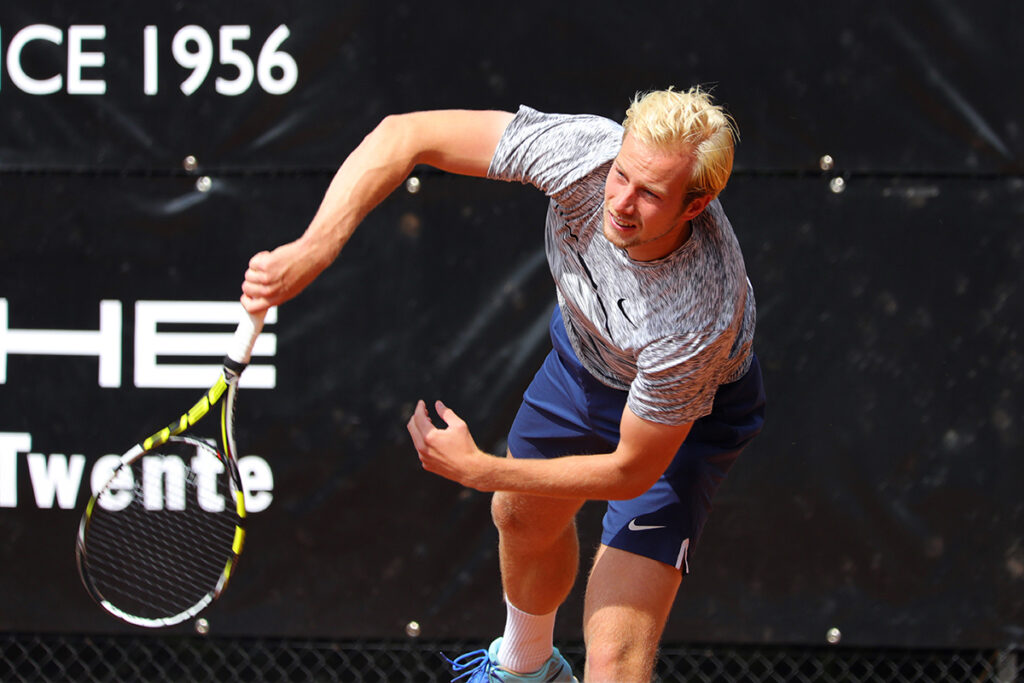 Tennisser slaat een opslag op de baan, sportfotografie