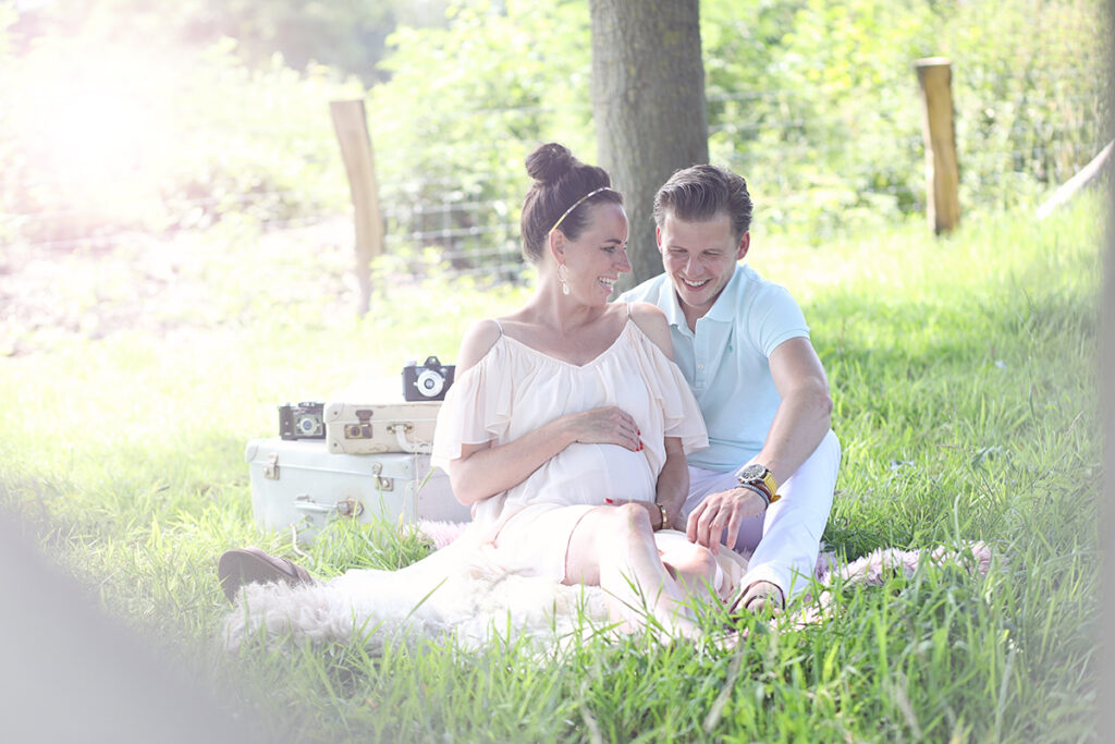 Zwanger stel bij een picknick in het gras, zwangerschapsshoot buiten