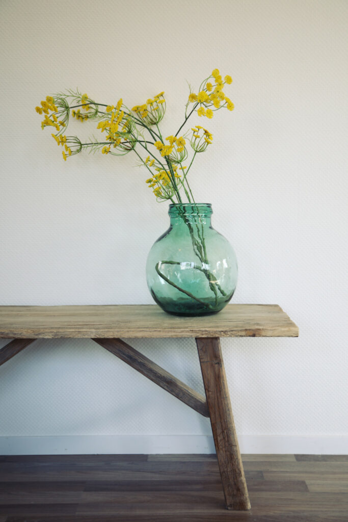 Houten wandtafel met vaas vol gele bloemen, interieurdetail