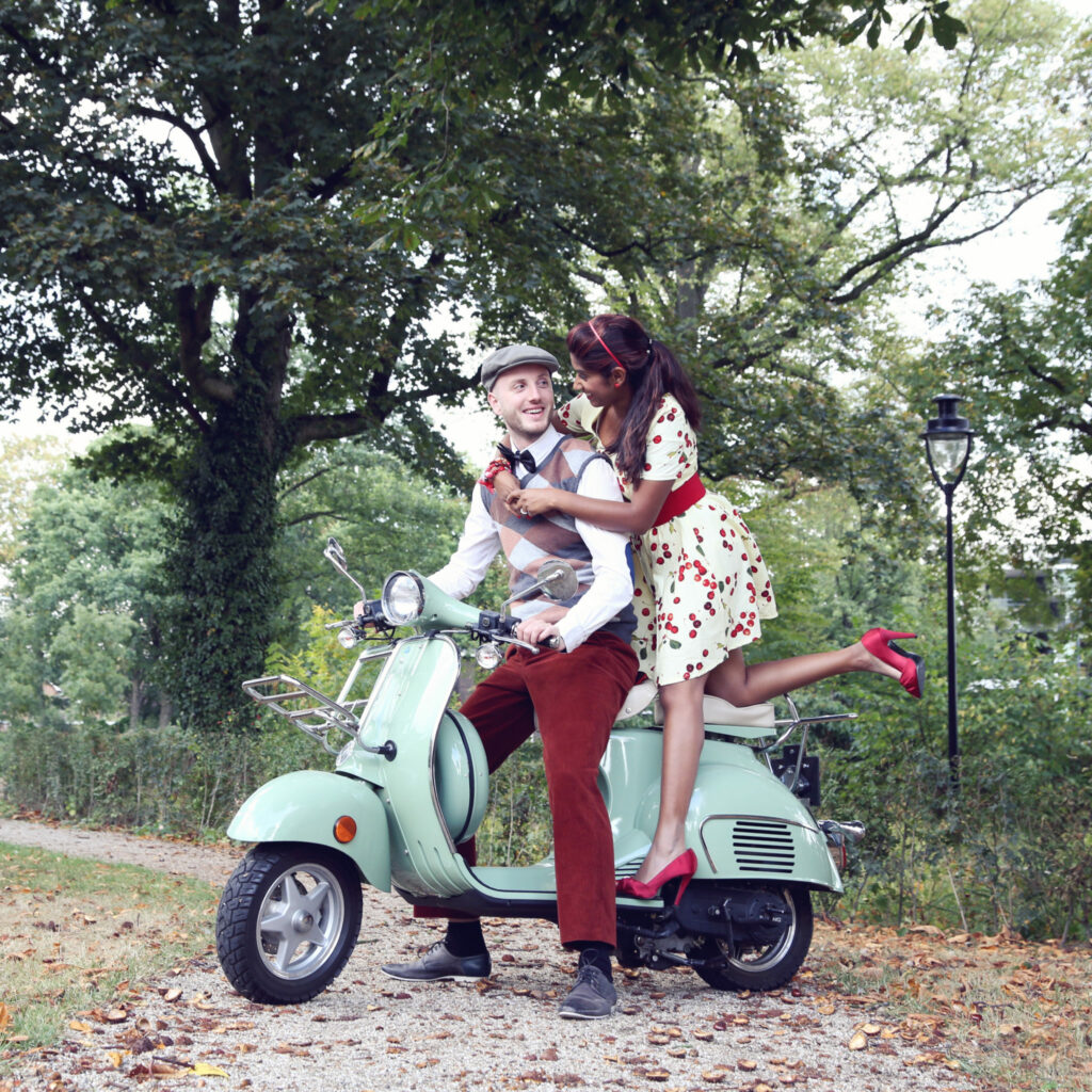 Stel in retrostijl op een mintgroene Vespa onder de bomen