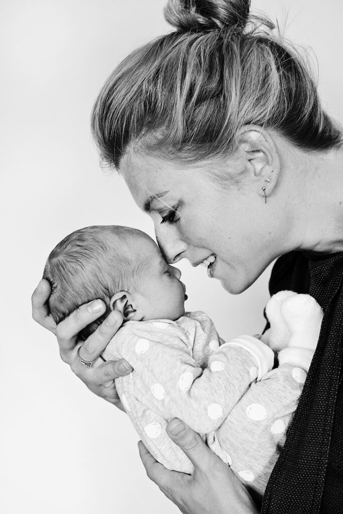 Zwart-witfoto van een moeder die haar pasgeboren baby een kus geeft