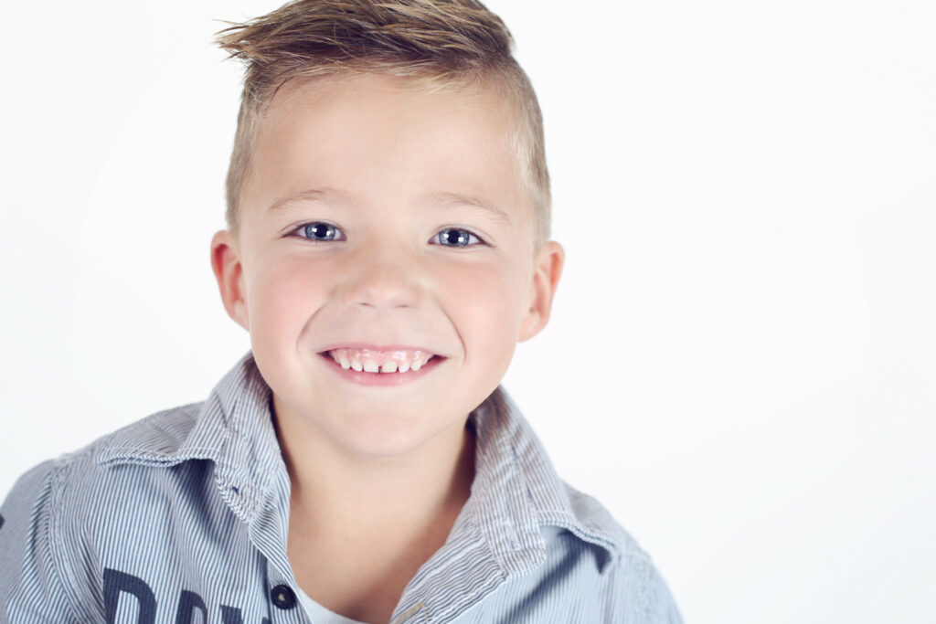 Portret van een lachende jongen met een stoer kapsel