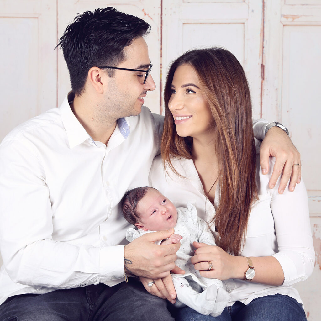 Ouders met hun pasgeboren baby op schoot, newborn fotoshoot