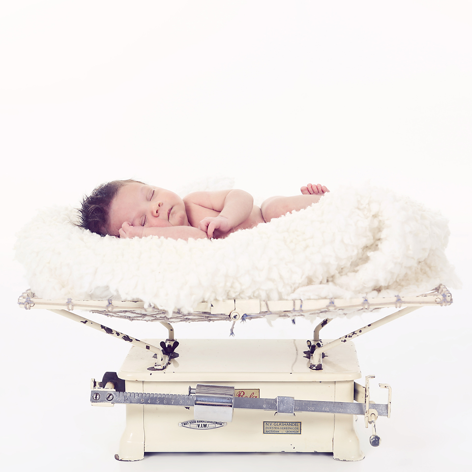 Newborn op een vachtje in een vintage babyweegschaal