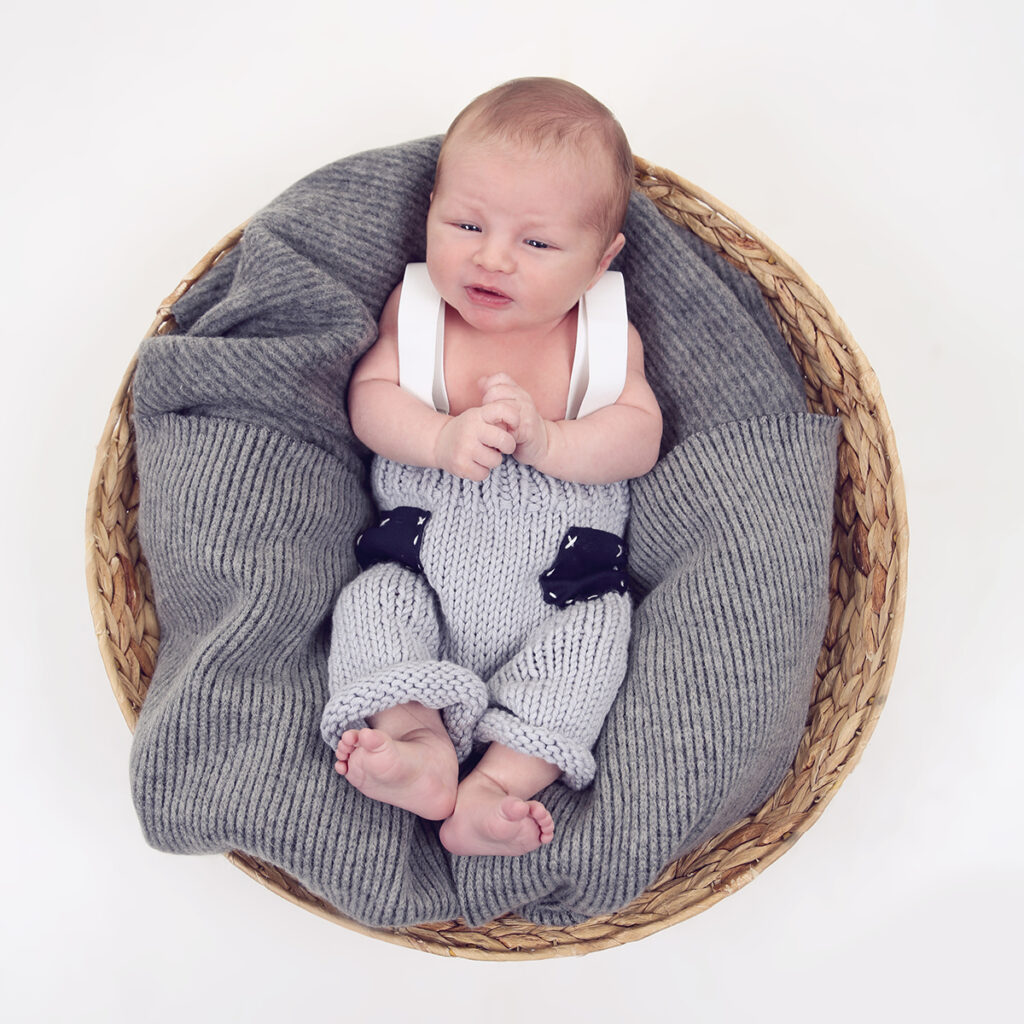 Newborn in tuinbroekje in een rieten mand, newborn shoot