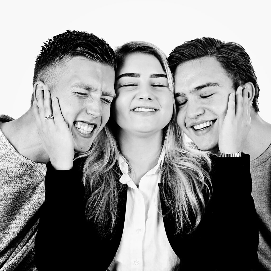 Zwart-witfoto van een zus tussen haar twee lachende broers