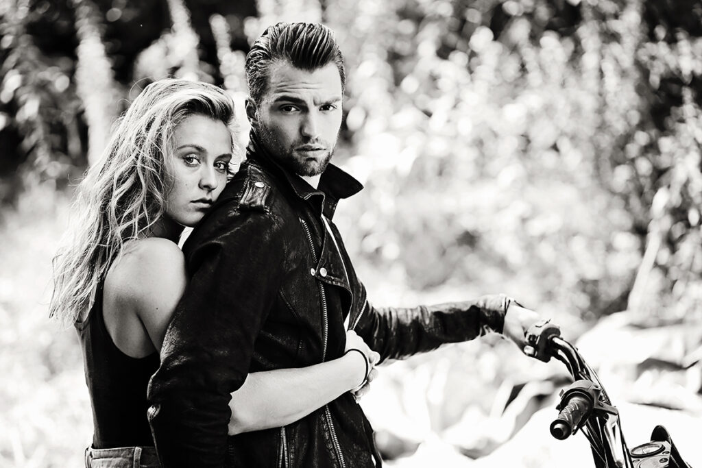 Zwart-witfoto van een stel bij een motor, stoere fashion shoot