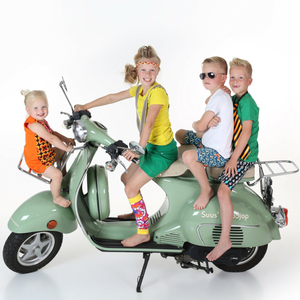 Vier kinderen op een mintgroene scooter in de witte studio