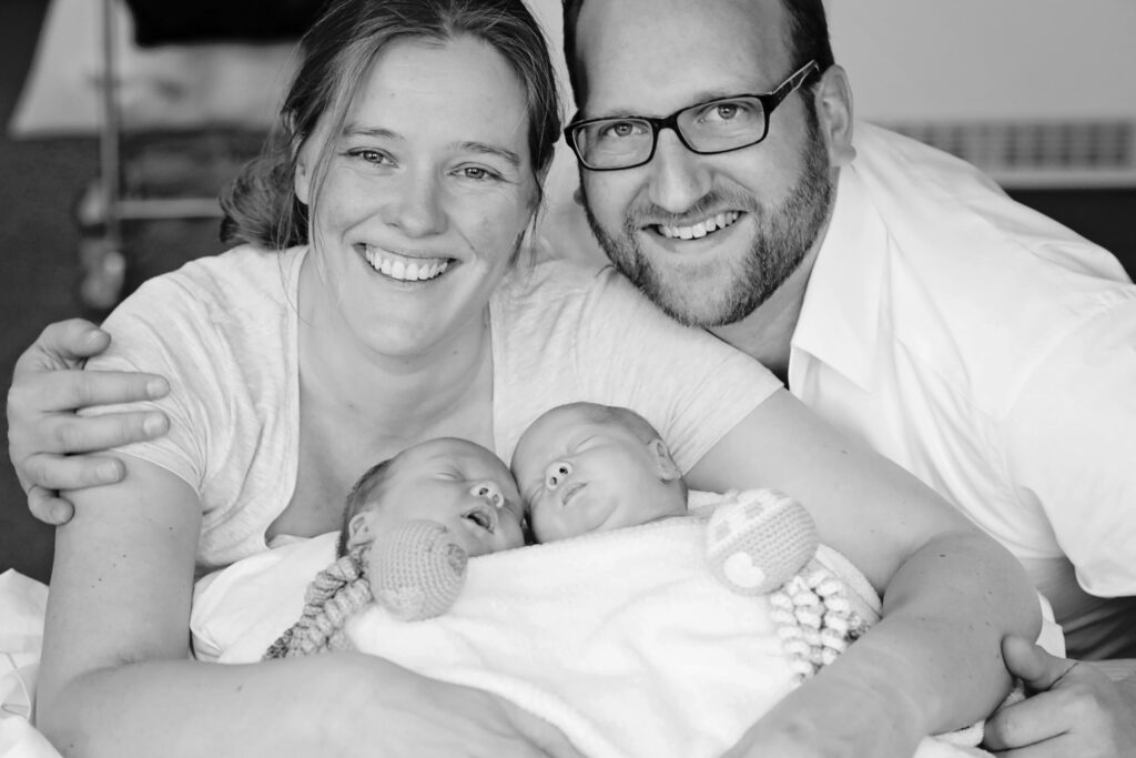 Zwart-witfoto van ouders met hun pasgeboren tweeling
