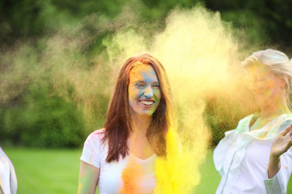Vrouw in een gele poederwolk tijdens een ColorPowder-fotoshoot