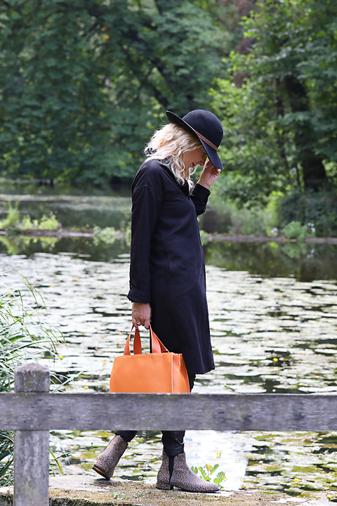Vrouw met oranje tas op een steiger aan het water, fashion productfoto