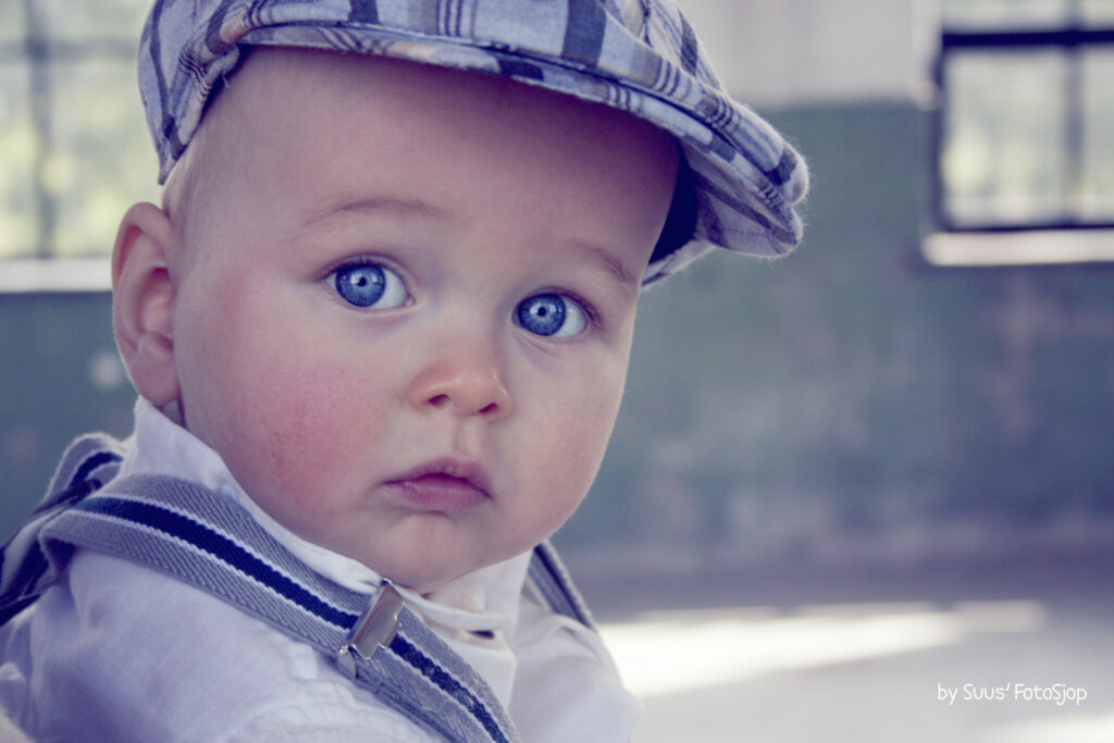 Peuter met blauwe ogen en een pet, kinderportret