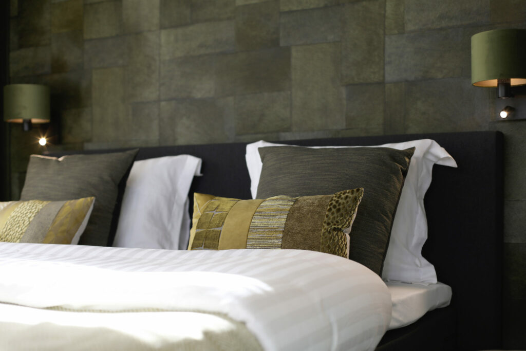 Hotelkamer met groene wand en opgemaakt bed