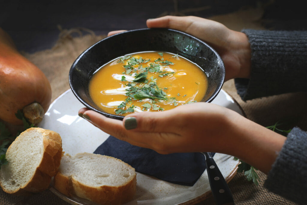 Handen houden een kom soep met brood vast, foodfotografie