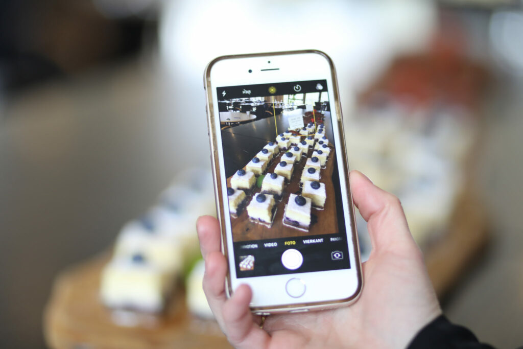 Hand fotografeert een gedekte tafel met de telefoon, social media food