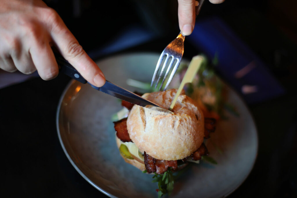 Hamburger wordt aangesneden op een bord, foodfotografie voor horeca