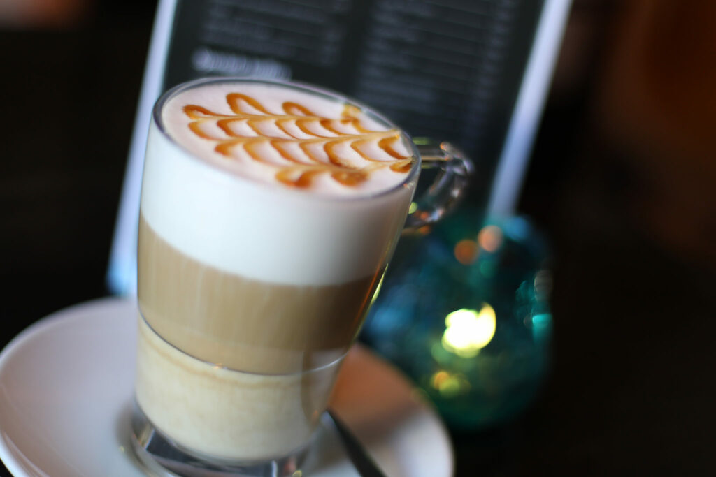 Latte macchiato in een hoog glas op een terrastafel