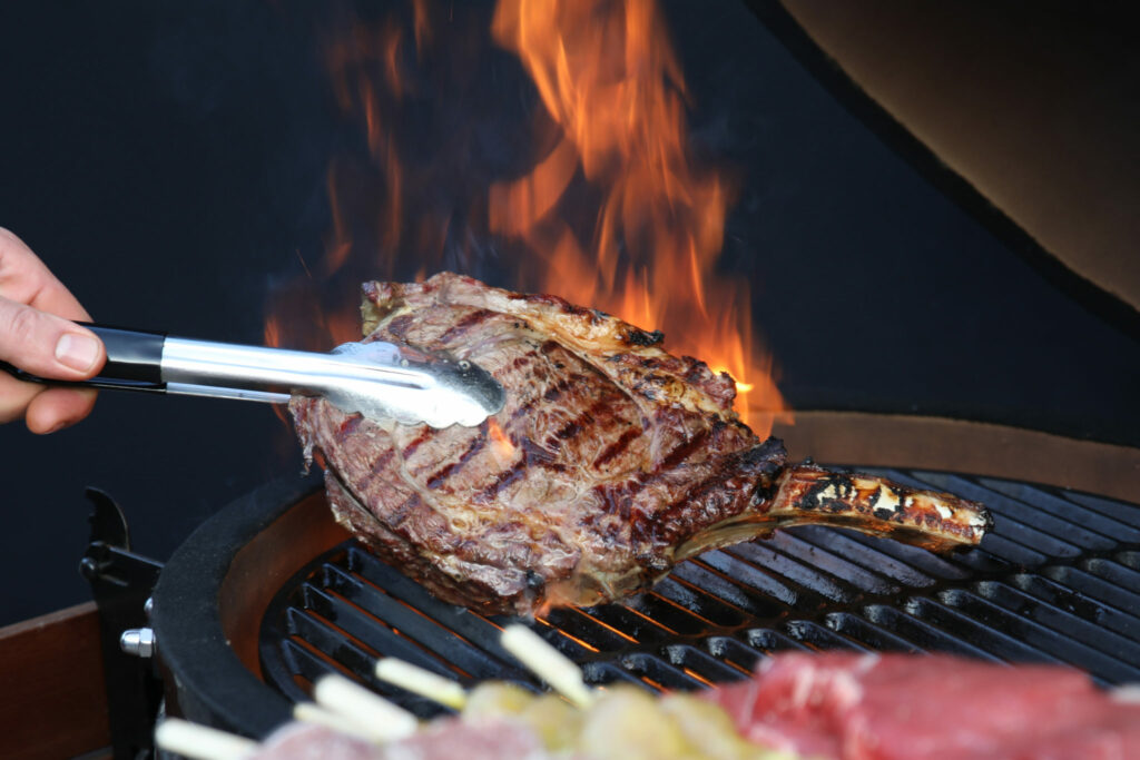 Steak op een vlammende grill met tang, foodfotografie