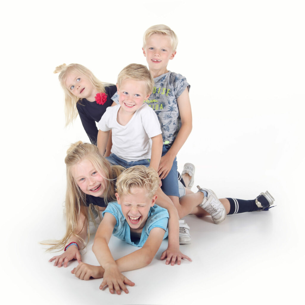 Vijf broertjes en zusjes stapelen speels op elkaar in de witte studio