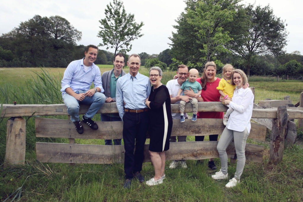 Grote familie bij een houten hek in het weiland, familieshoot