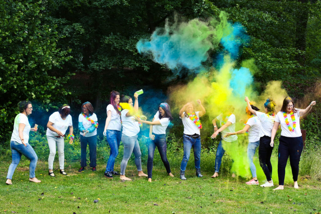Groep vriendinnen gooit kleurenpoeder in de lucht in een tuin