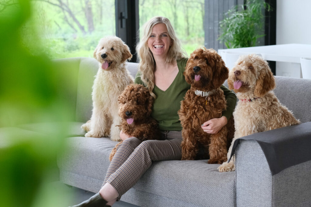 Vrouw op de bank met drie labradoodles thuis