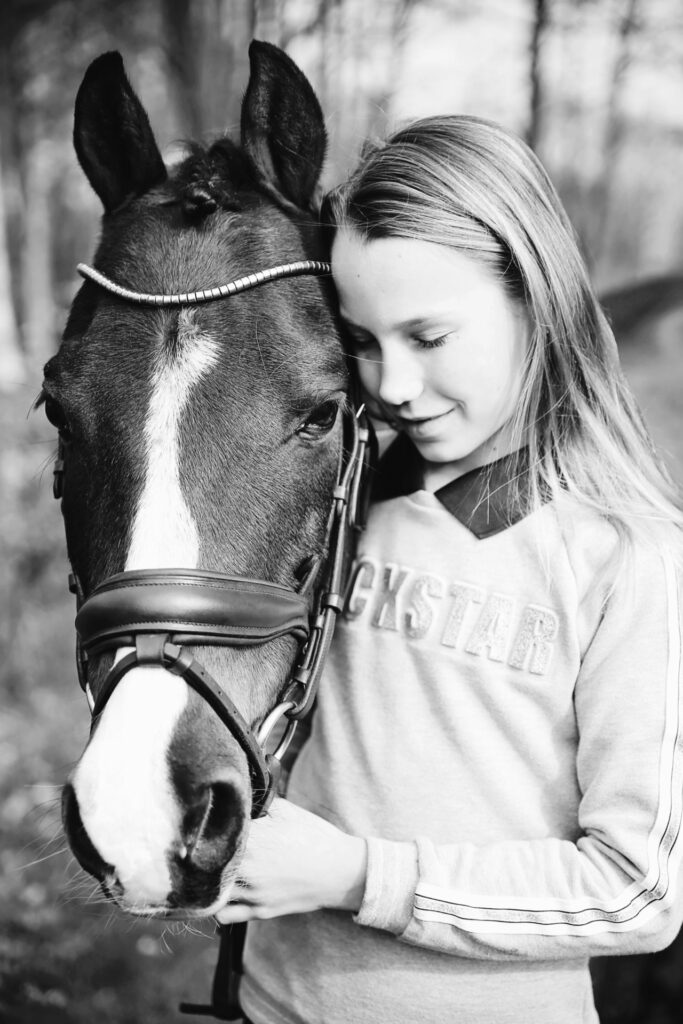 Zwart-witfoto van een meisje met haar paard, hoofd tegen hoofd