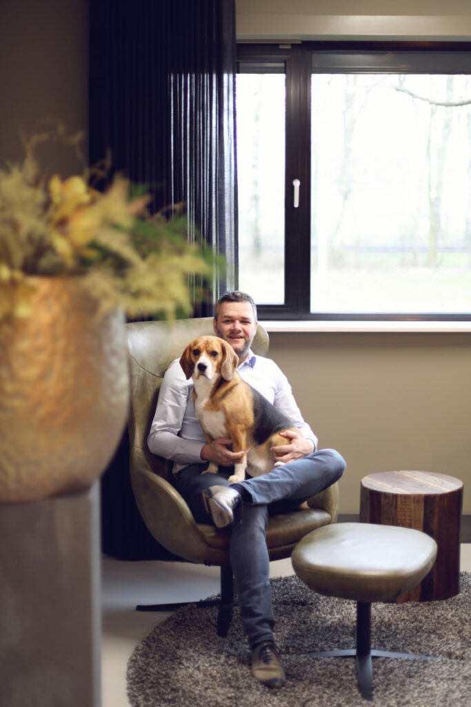 Man met zijn hond op schoot in een stoere fauteuil, huisdierfotografie thuis