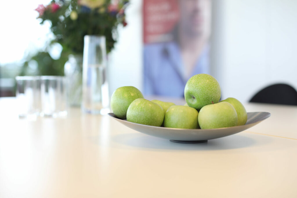 Schaal met groene appels op een vergadertafel, sfeerfoto kantoor