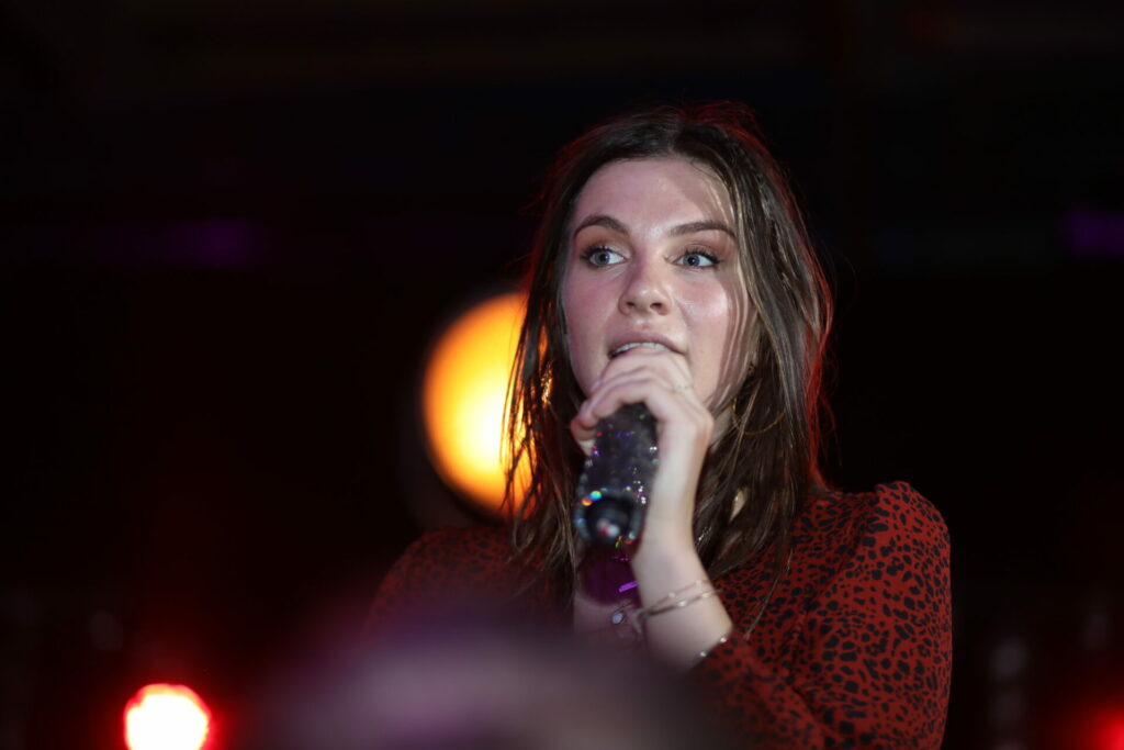 Zangeres zingt in een microfoon op het podium, evenementfotografie