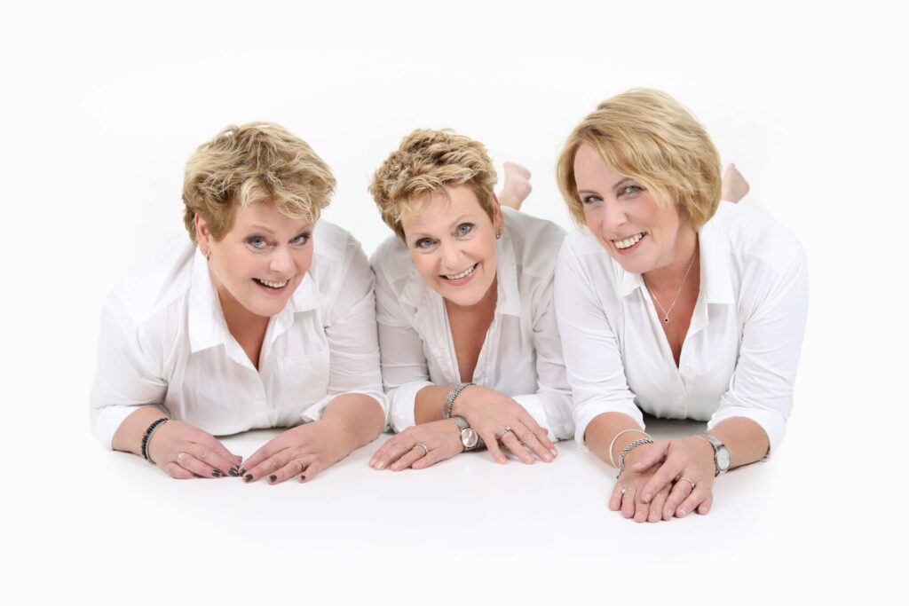 Drie generaties vrouwen in wit liggen lachend op de studiovloer