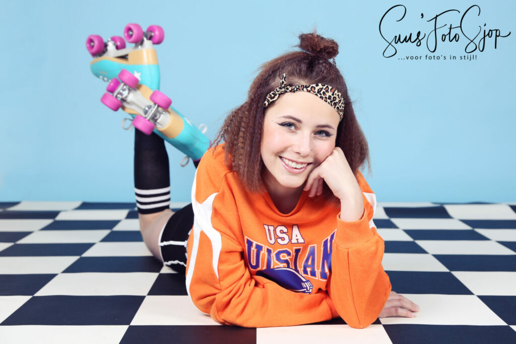 Meisje op rolschaatsen in een retro studiodecor met geblokte vloer