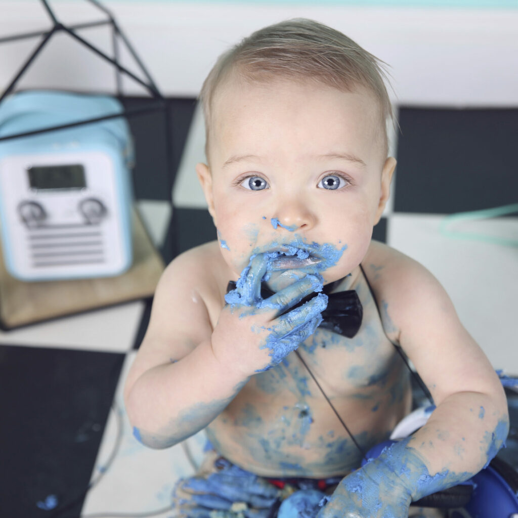 Baby met blauwe taart op zijn gezicht tijdens een cakesmash-fotoshoot