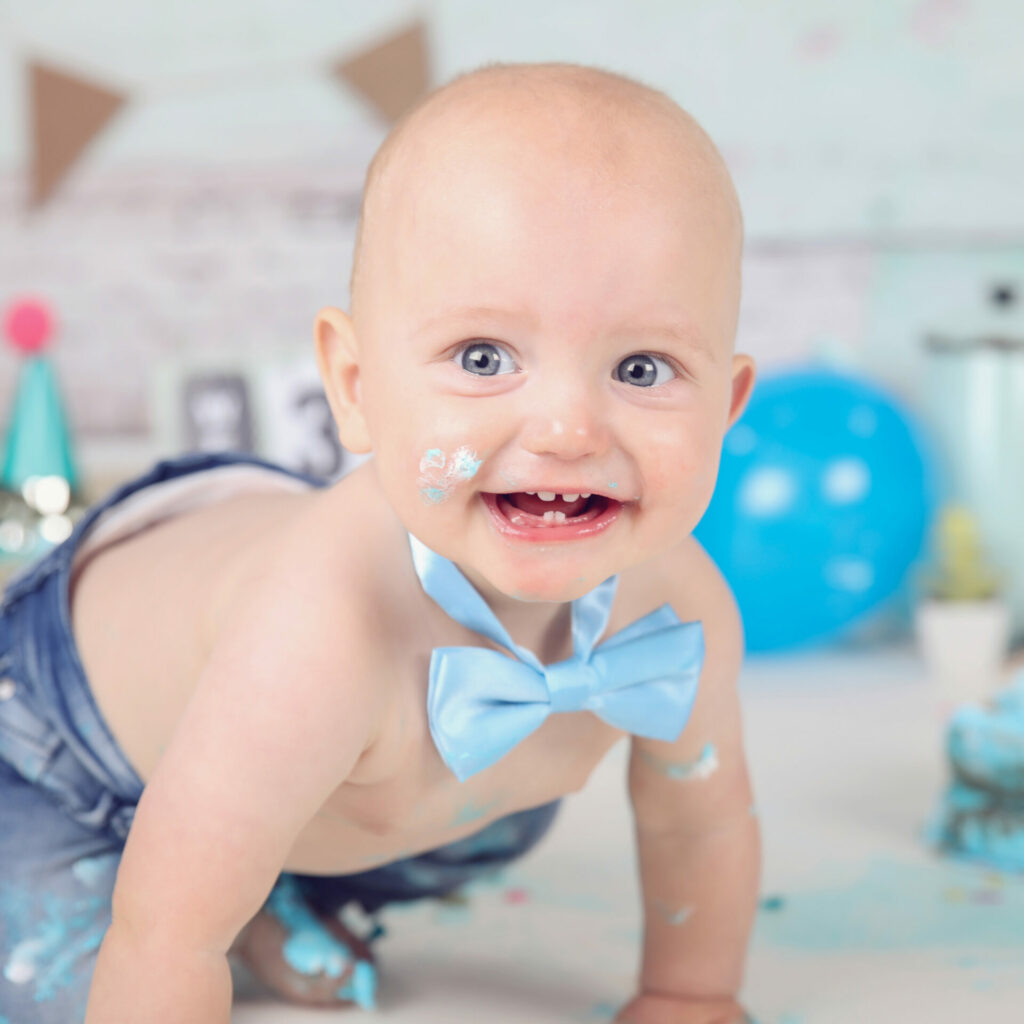 Lachende baby met blauwe strik kruipt tijdens een cakesmash in de studio